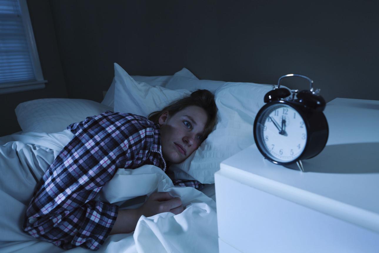 Quarto escuro à noite, pessoa acordada sem conseguir dormir