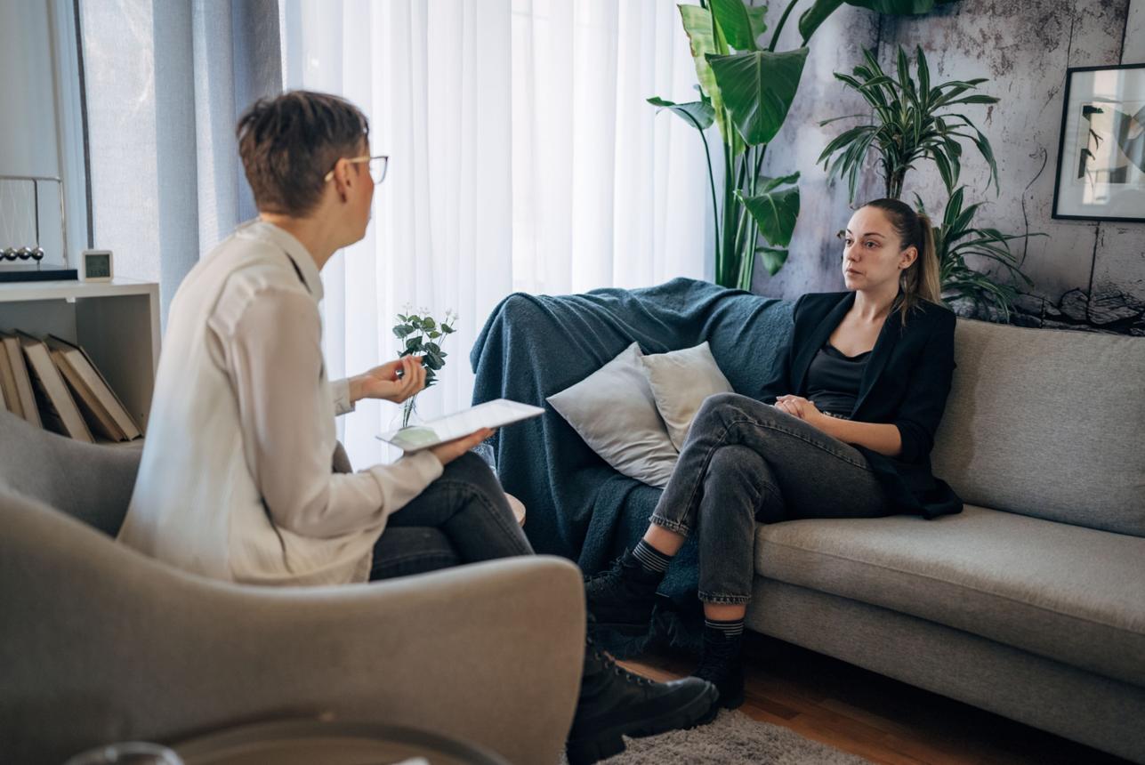 Sessão de psicoterapia: psicóloga com prancheta e paciente conversando em uma sala acolhedora e iluminada